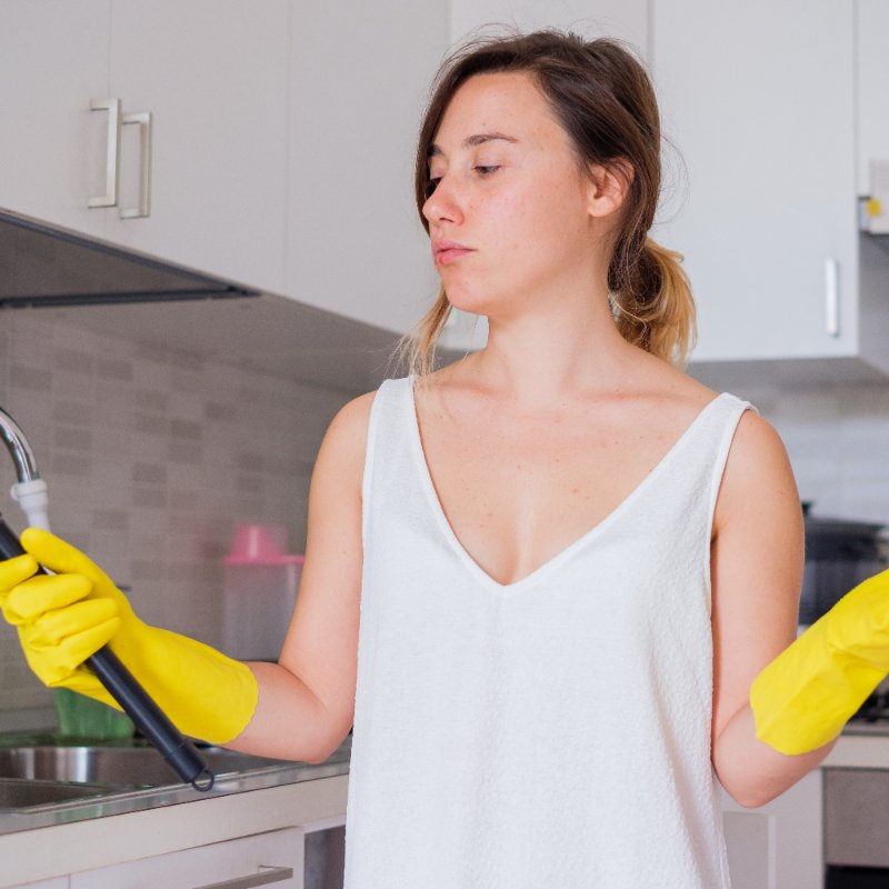 young woman plunging a clogged sink