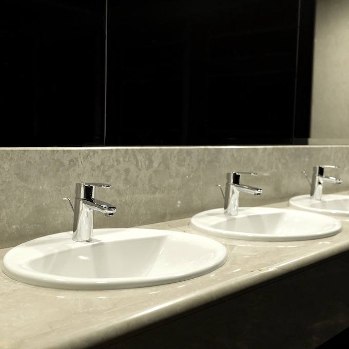 A line of faucets seen in a clean public bathroom