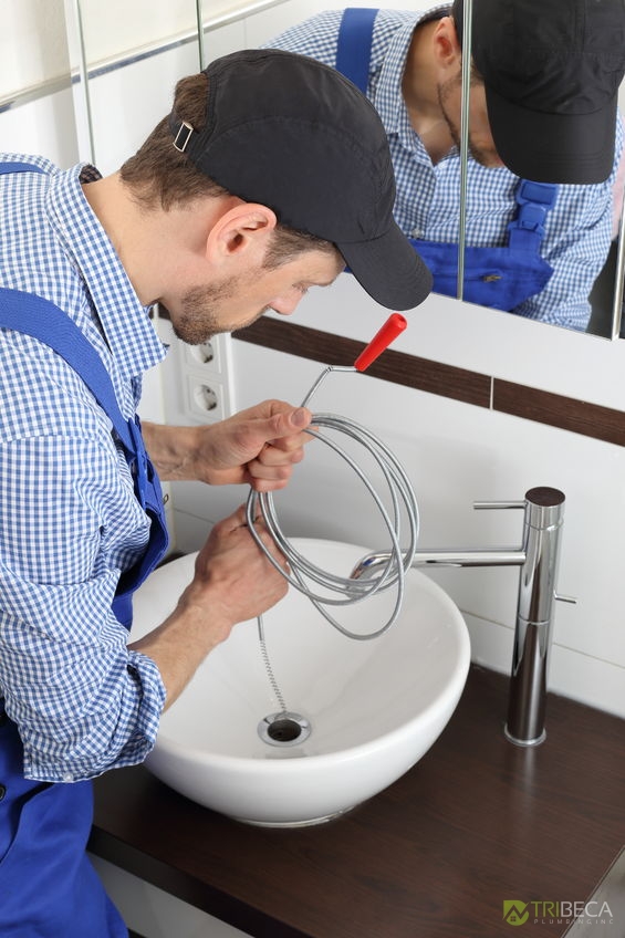 a caucasian plumber cleaning a pipe drain with a spiral